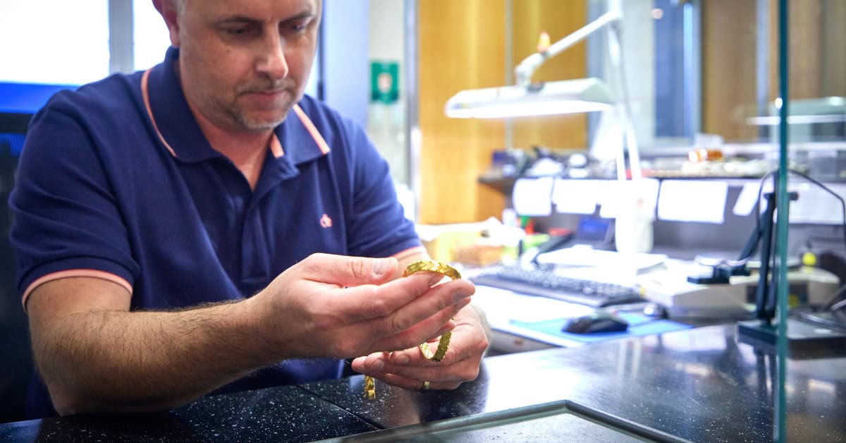 Schätzer an seinem Platz hält Goldkette zur Bewertung in der Hand