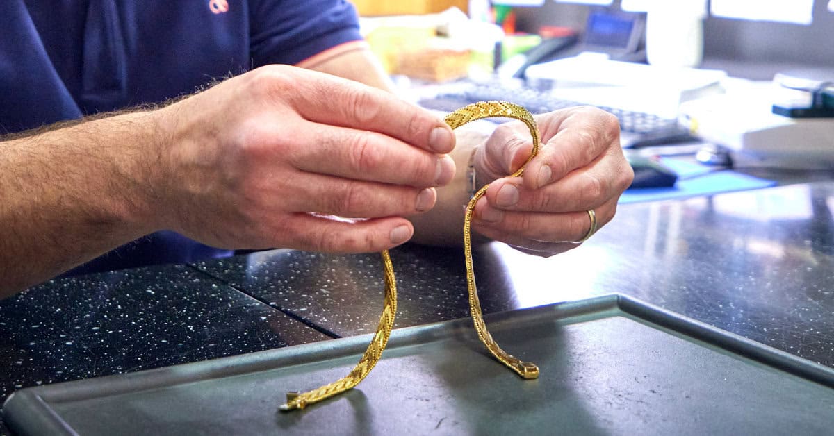 Eine Goldkette in den Händen eines Schätzers im Leihamt